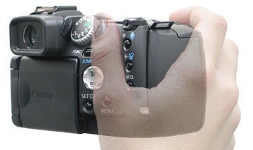 Close-up photo of a person's hand holding the Canon PowerShot Pro1 camera, focusing on the camera's controls and design.