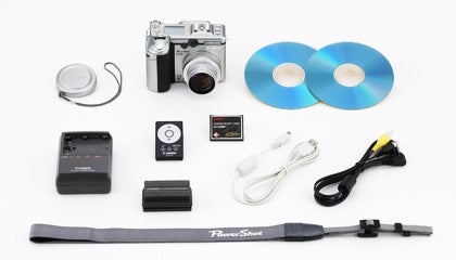 An array of Canon PowerShot G6 camera accessories displayed on a white background, including the camera itself, two CDs, a battery charger, a remote control, a memory card, cables, and a camera strap with 