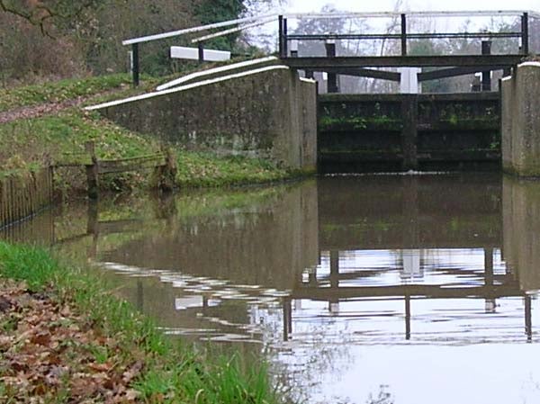 Photograph taken with Nikon CoolPix 4800 showcasing a serene canal scene with a lock gate, reflections on the water surface, and surrounding foliage.