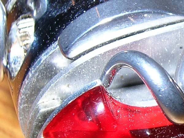 Close-up of a silver and red object with reflective surfaces and noticeable dust particles