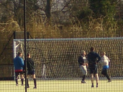 Photo taken with a Casio Exilim Zoom EX-Z50 Digital Camera showing a group of people playing football on an outdoor field with a net in the background.