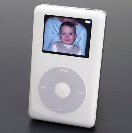 White Apple iPod Photo displaying a baby's picture on its screen, with the classic click wheel interface below the screen, set against a grey background.