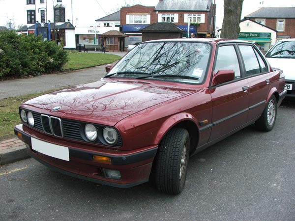 A red BMW car parked on the side of a street, possibly a photo taken with the Fujifilm FinePix S5500 camera.