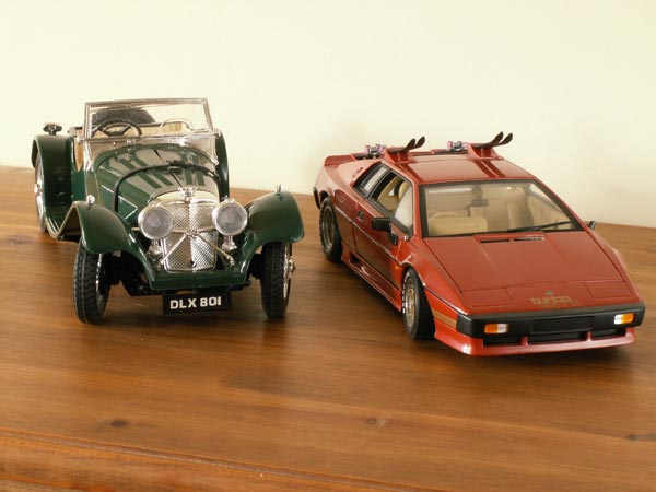 Two detailed model cars, a classic green convertible and a modern red sports car, displayed on a wooden surface, photographed with a Konica Minolta DiMAGE Z5 camera.
