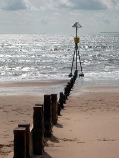 Seascape photography sample from Nikon Coolpix 7900 digital camera showcasing the camera's ability to capture contrast of a groyne leading into the sea under bright daylight conditions.