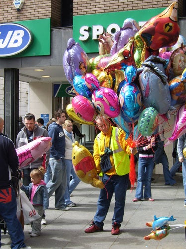 Person selling colorful balloons on busy street.Colorful balloons with cartoon character print photographed indoors.