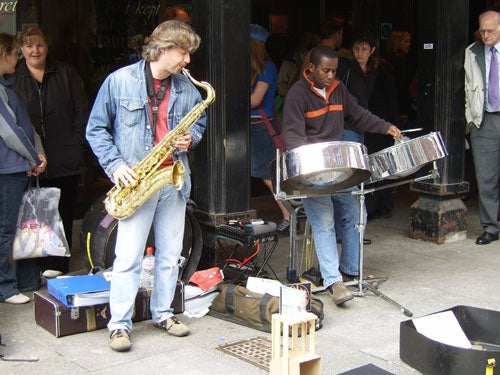 Street musicians playing saxophone and steelpan.