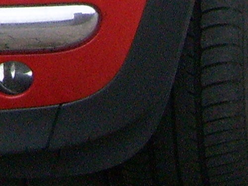 Close-up of a car tire and red bumper.