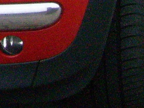 Close-up of a car's red rear bumper and tire.