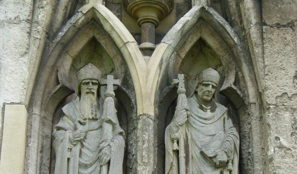 Photograph taken with Ricoh Caplio R1V digital camera showcasing two stone statues of figures with religious insignia on an ornate gothic architectural facade.Comparison of image quality at varying ISO levels from the Ricoh Caplio R1V Digital Camera, showing a stone sculpture at ISO 64, 100, 200, 400, and 800 with increasing noise and graininess at higher ISO values.