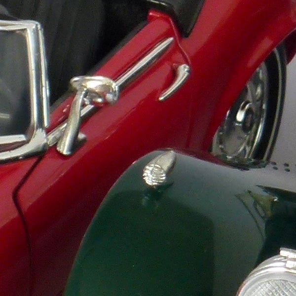 Close-up of a classic red car's side mirror and chrome door detail, possibly related to a review or feature of the MV Mobeus 1.6M product.