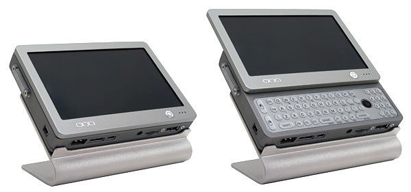 Two OQO model 01 Pocket Size PCs displayed side by side, one closed and the other open revealing its tiny QWERTY keyboard, set on integrated silver stands.