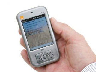 Hand holding an Orange SPV M500 Smartphone displaying the home screen.