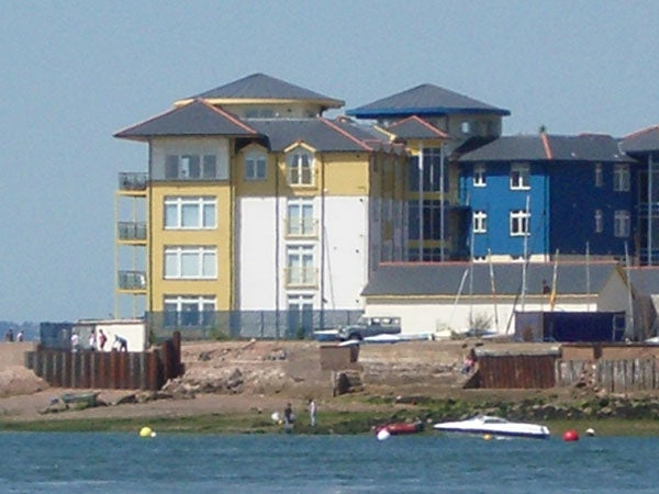 Photo taken with the Pentax Optio S5z camera showcasing a coastal scene with colorful apartment buildings and people engaging in leisure activities by the water.Close-up of a house roof captured with Pentax Optio S5z camera illustrating image quality and zoom capabilities.