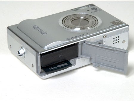 Fujifilm FinePix F10 digital camera with the battery compartment open, showing the battery and memory card slot against a white background.