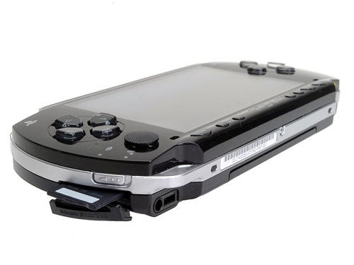 Close-up of a black Sony PlayStation Portable (PSP) with the UMD (Universal Media Disc) drive open, showing control buttons and screen.