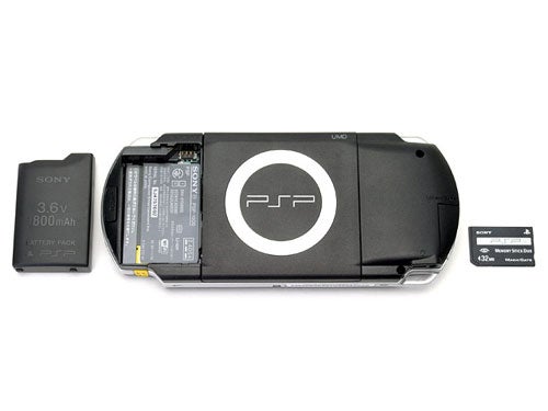 Sony PlayStation Portable (PSP) with the battery compartment open showing the battery and a Memory Stick Duo accessory beside it.