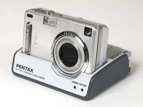 Pentax Optio SVi digital camera displayed on a battery charging stand.