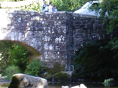 Photo taken with Pentax Optio SVi digital camera showing an old stone bridge over a stream with people standing on top.