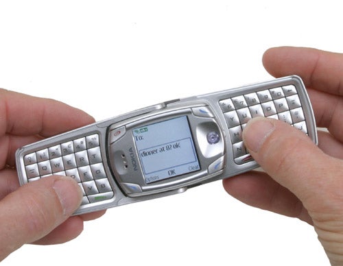 Hands holding a Nokia 6822 mobile phone with an open flip keyboard.