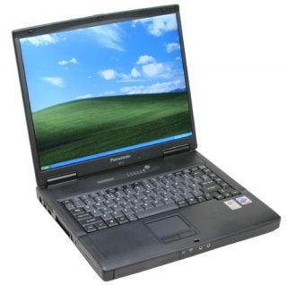Panasonic ToughBook CF-51 semi-rugged notebook open on a table displaying its screen with a landscape wallpaper, full keyboard, and touchpad.