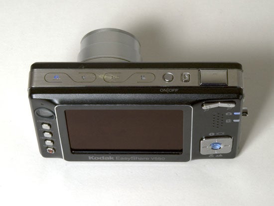 Kodak EasyShare V550 digital camera lying on a surface viewed from the back, displaying a large LCD screen, control buttons, and branding.