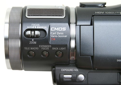 Close-up of a Sony HDR-HC1E High Definition Camcorder focusing on the lens with Carl Zeiss Vario-Sonnar branding and controls for focus, zoom, and exposure.