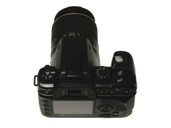 Konica Minolta Dynax 5D digital SLR camera with a zoom lens attached, viewed from the top showing control dials and buttons.