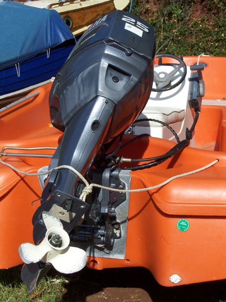 Outboard motor mounted on the back of an orange boat.