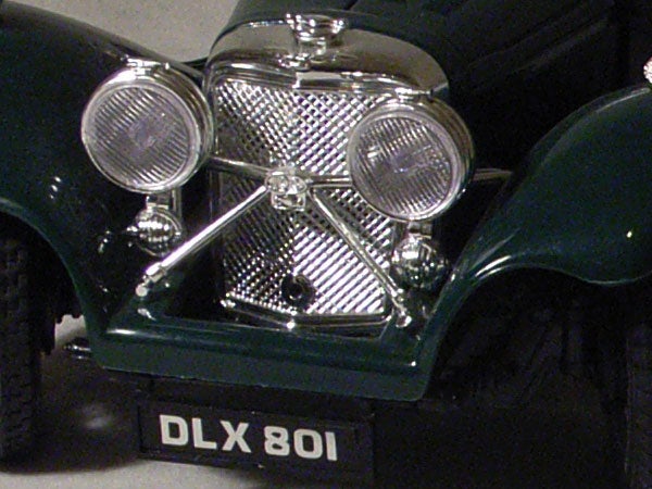 Close-up of a vintage car's front grille and headlights with the license plate reading DLX 801.
