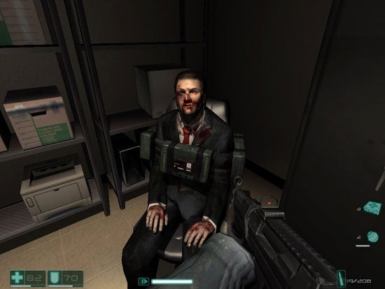 In-game screenshot showing a character from F.E.A.R. First Encounter Assault Recon sitting in an office chair with a bloodied face, viewed from a first-person perspective with a visible health and ammo HUD.