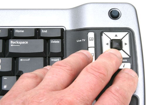 Close-up of a person's hand using the directional pad on a Microsoft Media Center 2005 Keyboard with dedicated Live TV button.