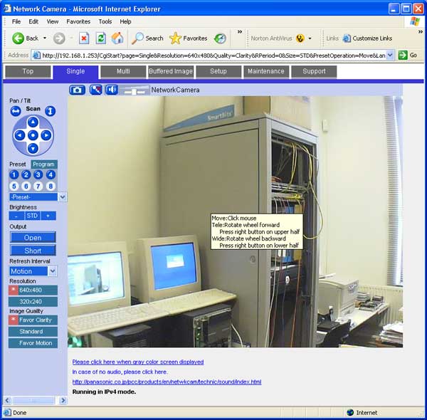 Screenshot of a Panasonic BB-HCM311 network camera user interface on a web browser, displaying a live feed of an office with two computer monitors on a desk and a server rack in the background.