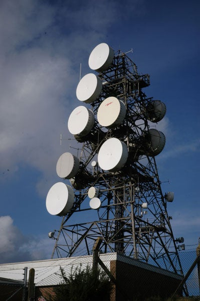 A photo of a tall communication tower with multiple satellite dishes against a partly cloudy sky, possibly taken with an Epson R-D1 digital rangefinder camera.