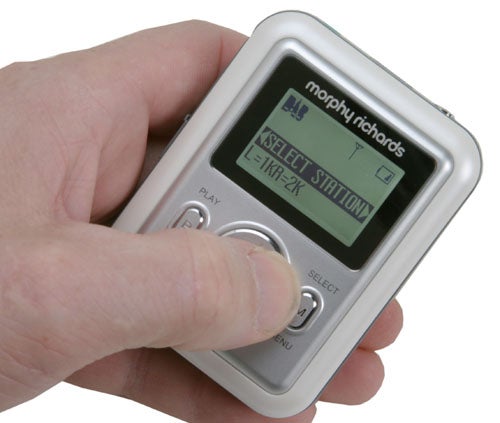 Hand holding a Morphy Richards 29200 DAB/FM MP3 Player with the display screen showing the "Select Station" menu.