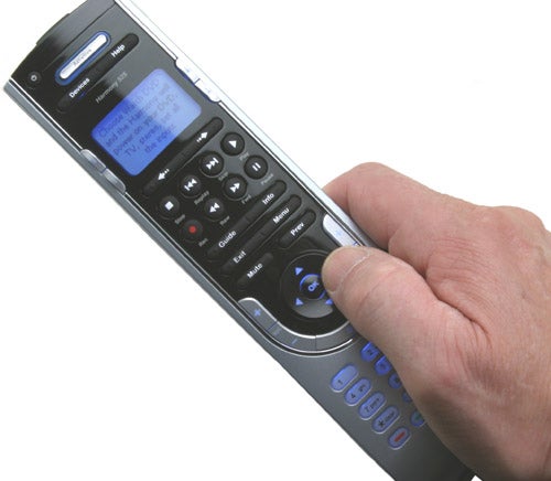 A person's hand holding a Logitech Harmony 525 Universal Remote with a visible display and buttons.