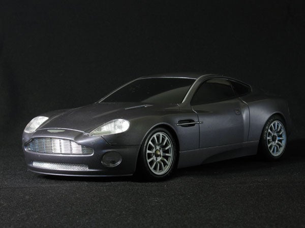 Scale model of a silver Aston Martin sports car on a black background.