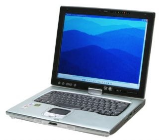 Acer TravelMate C312XMi tablet PC with swivel screen displaying blue hills wallpaper, the keyboard visible, and the trackpad and stylus holder in the center.