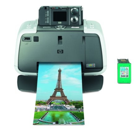 HP Photosmart 422 printer with a printed photo of the Eiffel Tower emerging from the output slot, alongside a green HP ink cartridge.