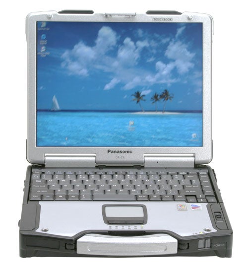 Panasonic ToughBook CF-29 rugged laptop with open lid showing screen displaying a tropical beach wallpaper, full keyboard, touchpad, and carry handle visible against a blurred background.