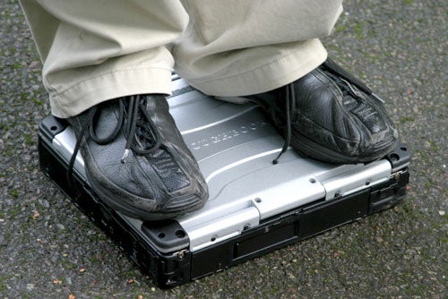 Person standing on a Panasonic ToughBook CF-29 to demonstrate its durability.