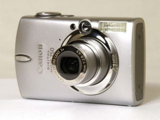 Canon Digital IXUS 750 camera positioned on a plain surface showcasing its compact design, lens, and flash.