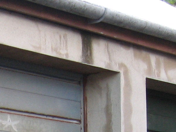 Sample photo demonstrating the zoom capability of the Canon Digital IXUS 750, showing a close-up of a building's corner with a gutter and water stains on the wall.
