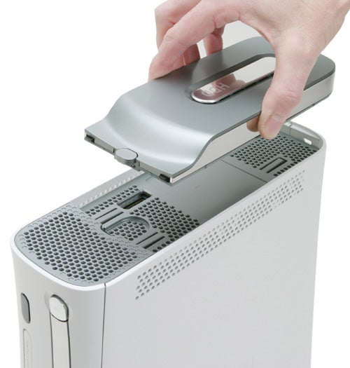 A person's hand removing the hard drive from a white Microsoft Xbox 360 video game console.