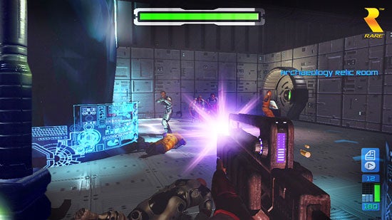 In-game screenshot from Perfect Dark Zero showing a first-person perspective with the player wielding a futuristic weapon in a firefight inside the Archaeology Relic Room.