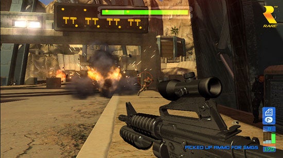 Screenshot of a gameplay moment from Perfect Dark Zero video game, showing a first-person perspective with a scoped rifle aimed down a street where an explosion has just occurred and an enemy is visible in the distance. HUD elements display health status, ammunition, and in-game messages.