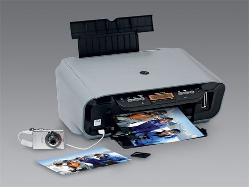 Canon Pixma MP170 inkjet printer with printed photos, memory card, and digital camera on a desk.