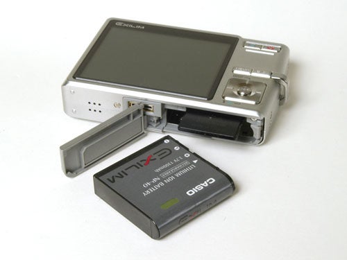 Casio Exilim EX-Z500 digital camera displayed with its large LCD screen open and a rechargeable lithium-ion battery lying in front of it.