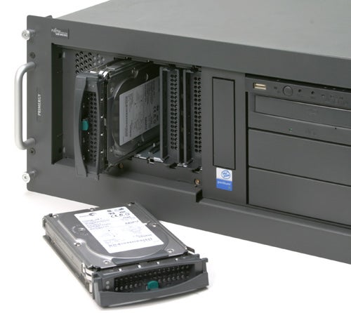 Fujitsu Siemens PRIMERGY TX150 S4 server with an open hard drive bay and a removed hard disk drive placed in front of it.