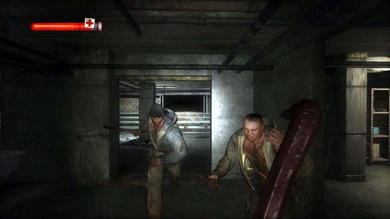 Screenshot from the video game Condemned: Criminal Origins showing a first-person view where the player character is facing two aggressive enemies in a dimly lit underground parking area. The player health bar is visible at the top left corner.